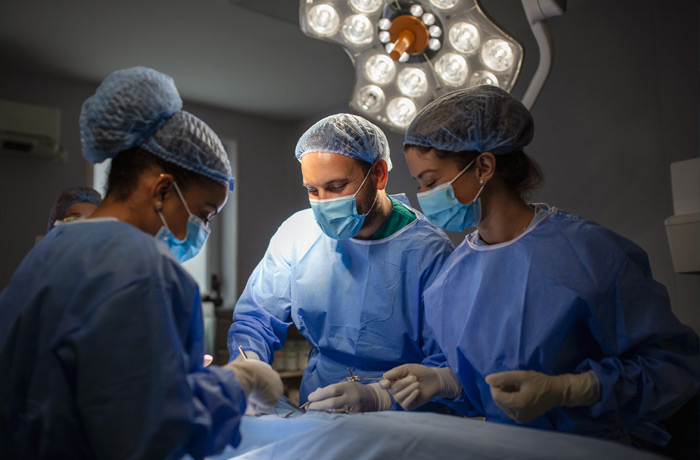 Image of three doctors performing surgery in an operating room.