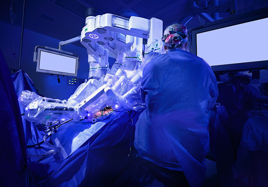 Medium wide image of a doctor looking at monitor in an operating room performing robotic surgery.