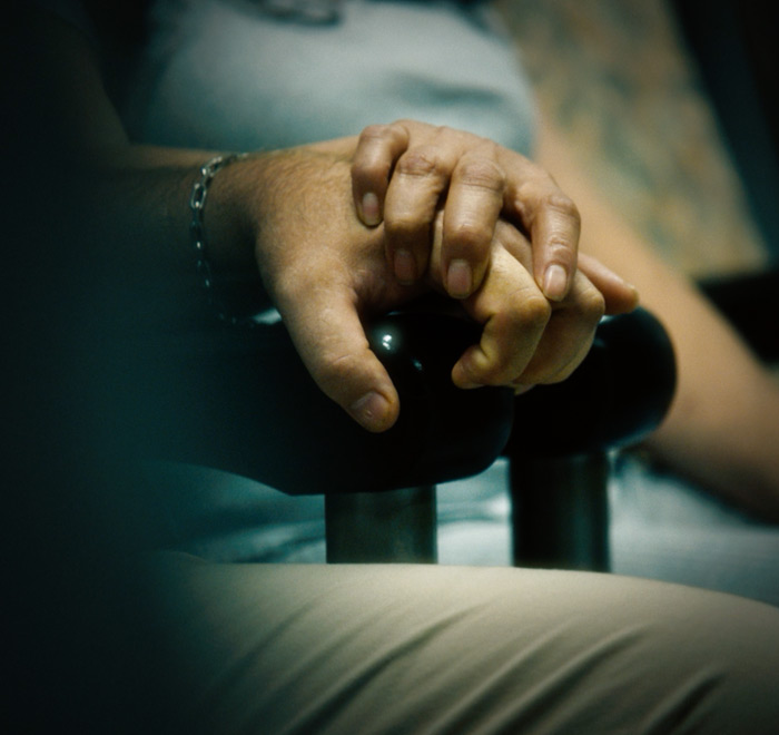 Close-up, vignetted image of a family member holding hands with a patient.