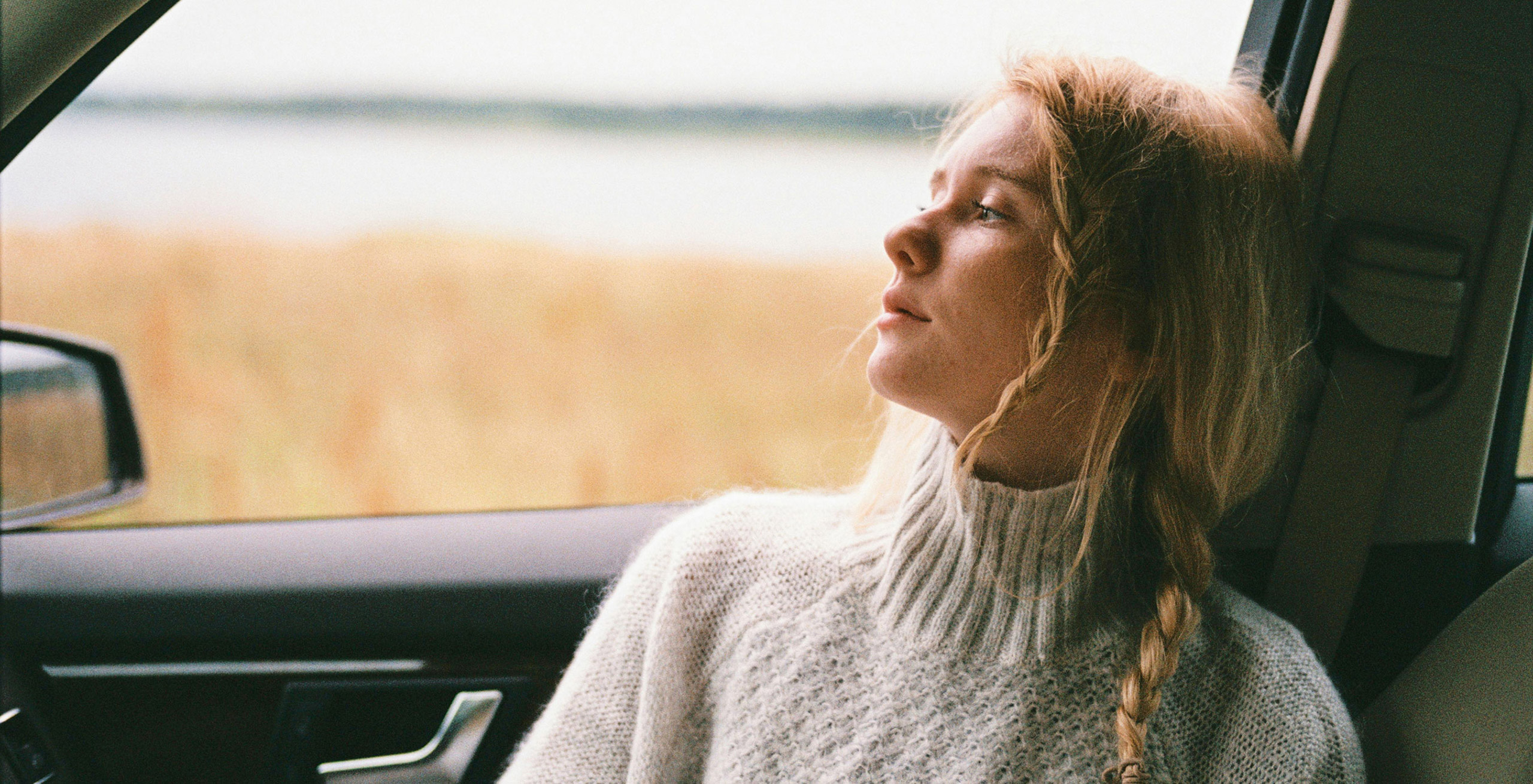 Image of a teen female sitting in the front passenger seat of a car.