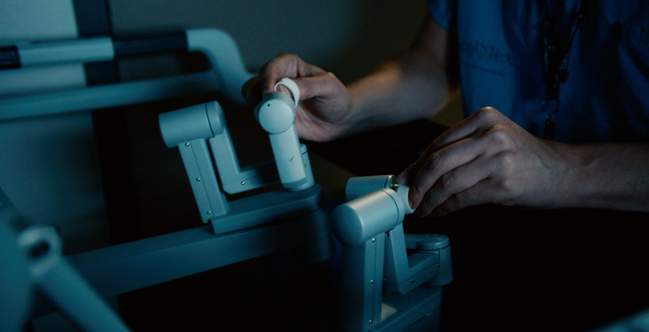 Close-up image of a surgeon’s hands operating a surgical robot.